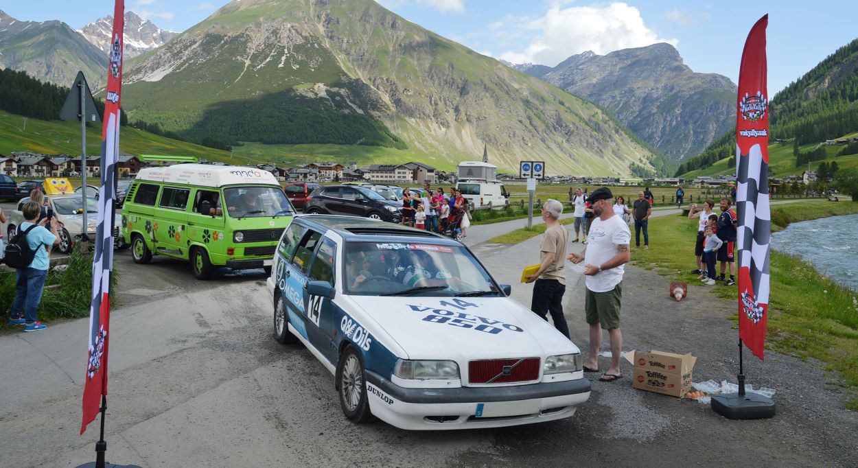 Banger rally car at finish line with mountains in background