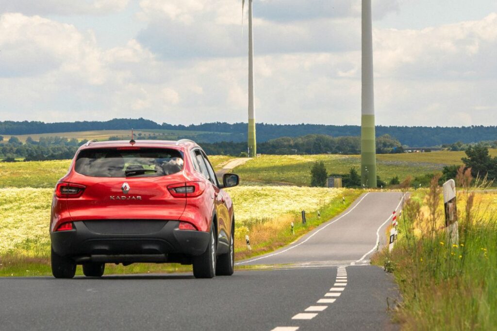 Red Renault Kadjar driving down a road