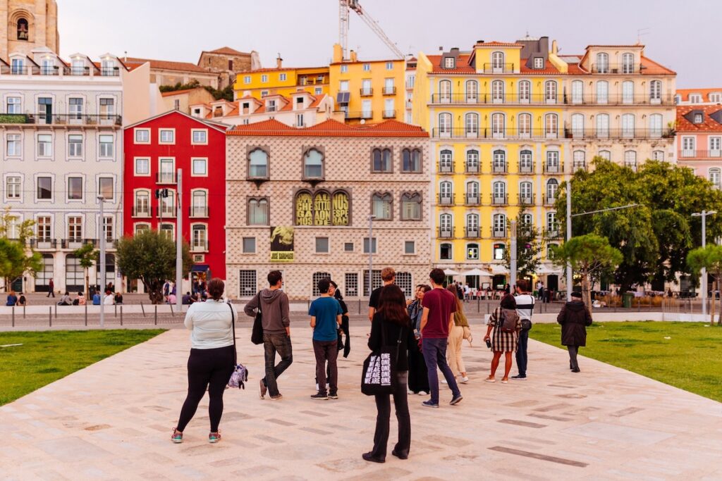 Image of a street in Lisbon, Portugal with people standing in front of buildings 