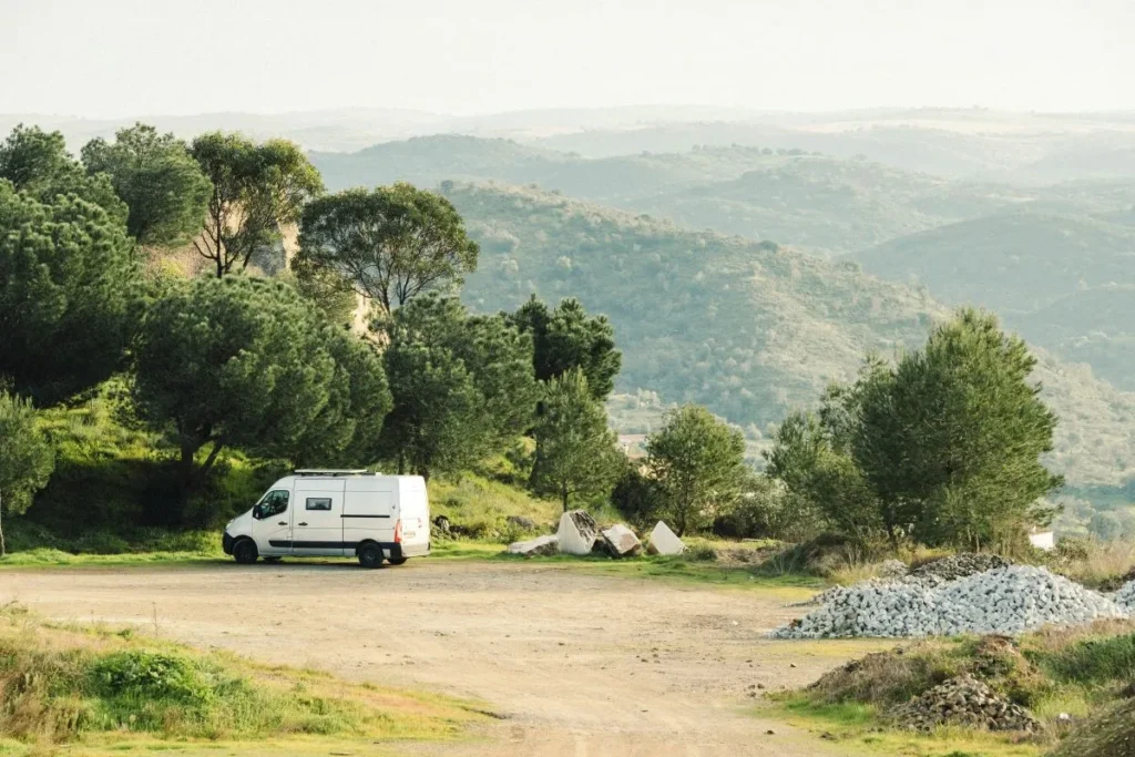 Campervan parked outside with a beautiful green view in the background of mountains and trees