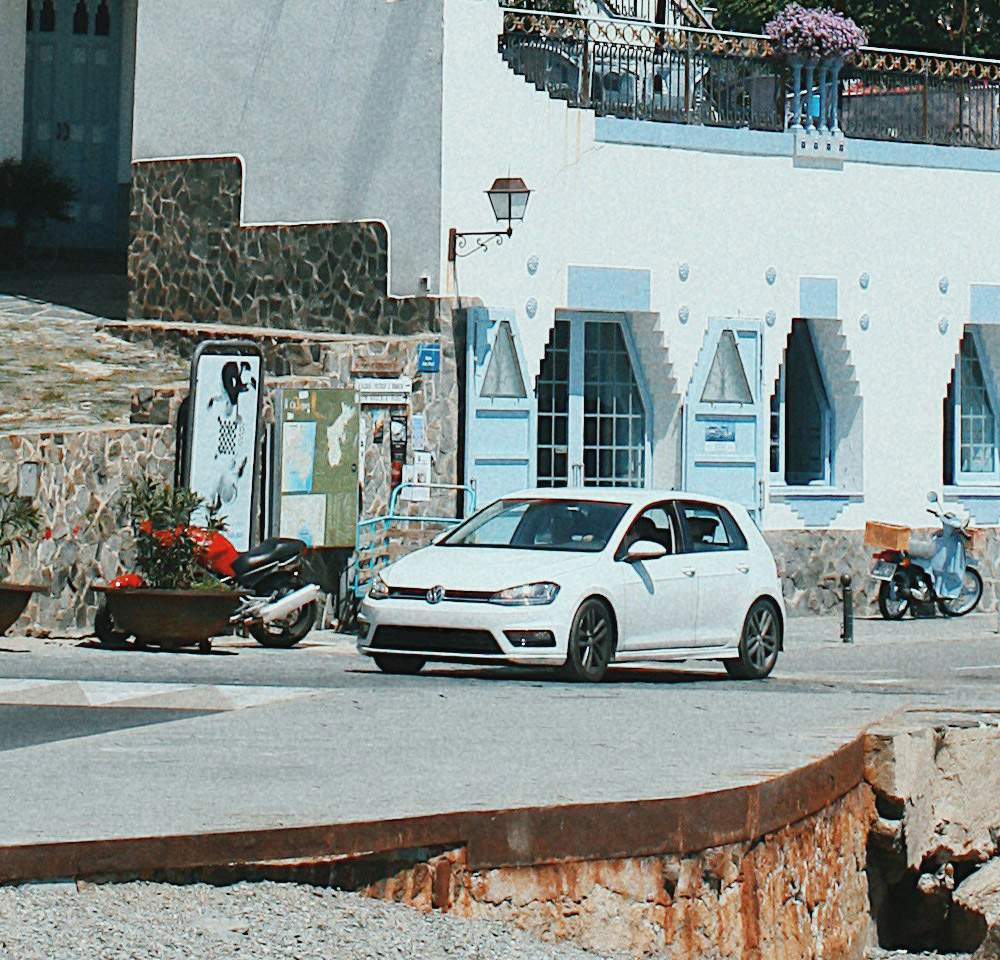 White VW driving along a foreign coast line
