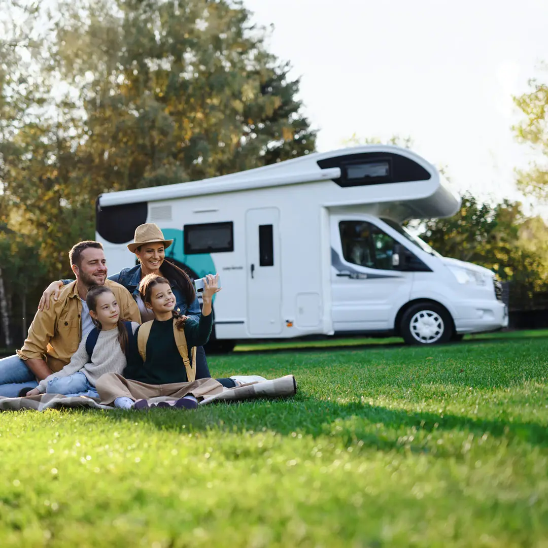 Family Sitting on Grass Outside of Motorhome